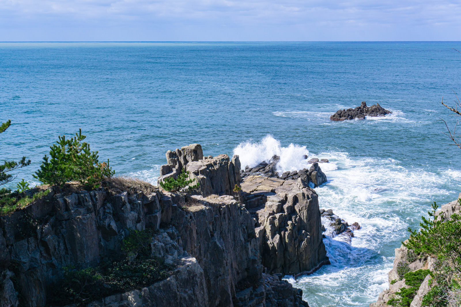 東尋坊の三段岩に打ち寄せる波が白い飛沫を上げている海の風景