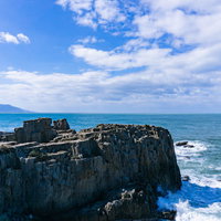 千畳敷前にそそり立つ岩壁といくつもの岩にぶつかり白く沸き立つ海の写真