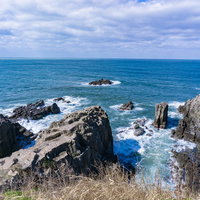 東尋坊の岩々に打ち寄せ飛び散る波しぶきの写真