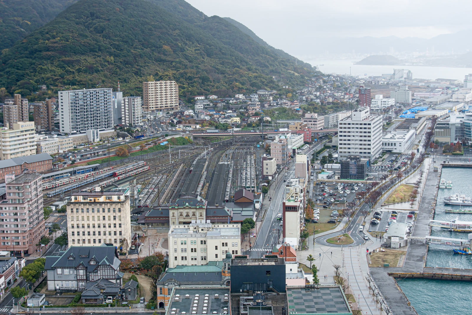 門司駅の建物と線路、その先に見える巌流島と海の風景