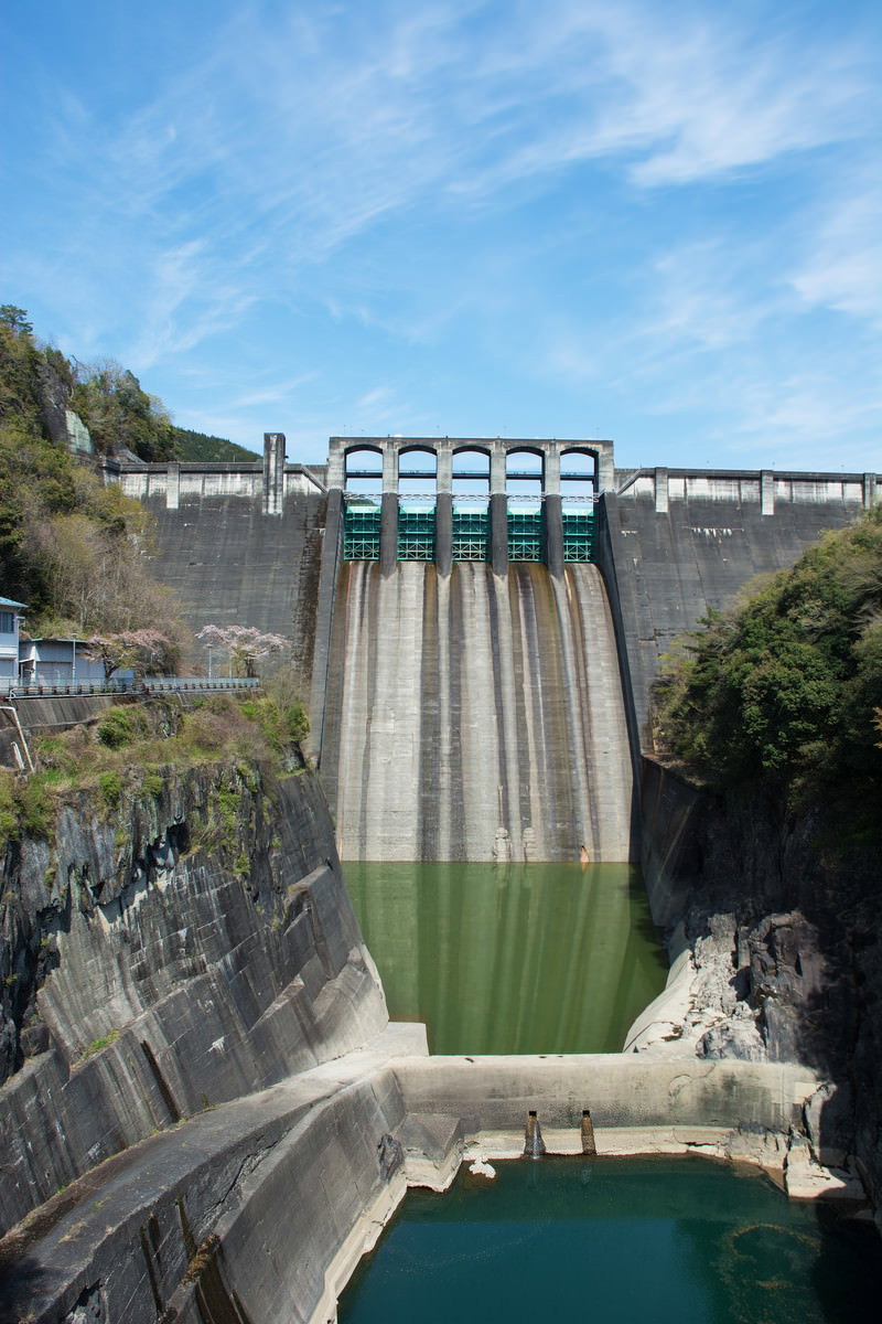 青空を背景にそびえ立つ白いコンクリート製の丸山ダム