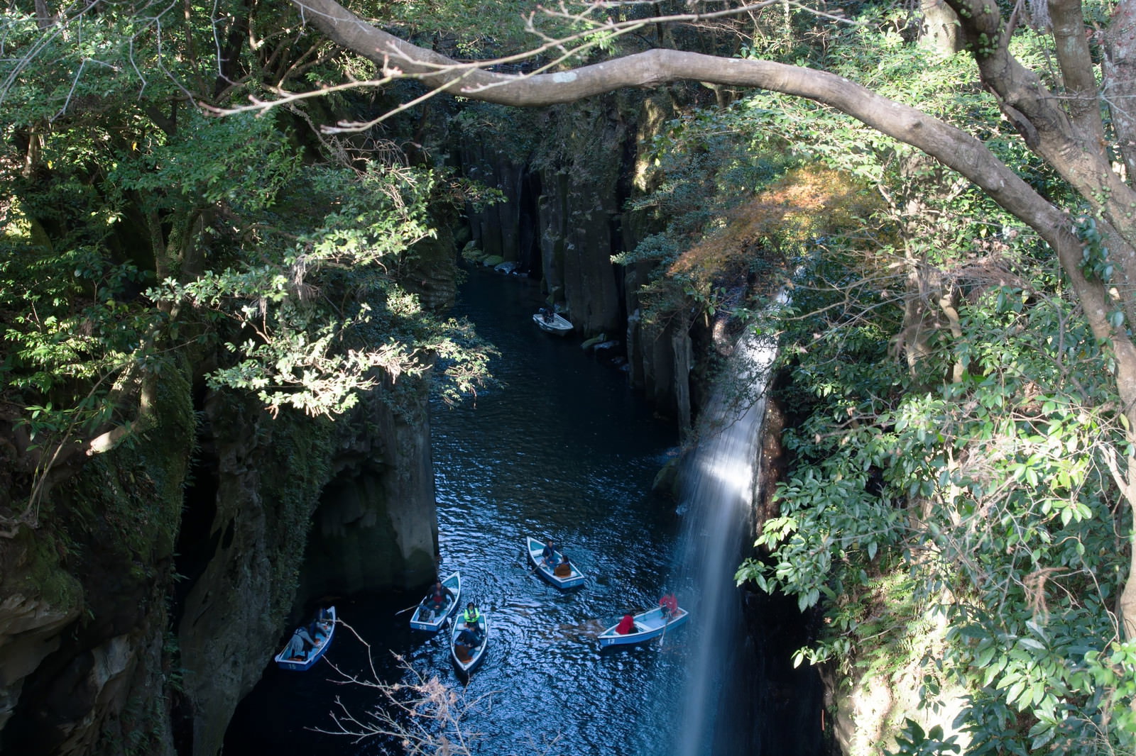 宮崎県高千穂町の真名井の滝がある峡谷で、エメラルドグリーンの川にボートが浮かぶ風景