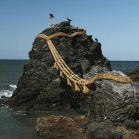 横から見た夫婦岩と奥に見える「かえる岩」の写真