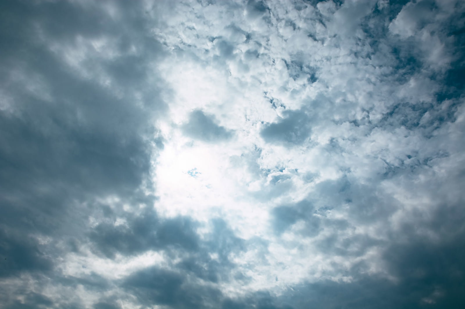 厚い灰色の雲に覆われた空に、雲の隙間から光が漏れている様子