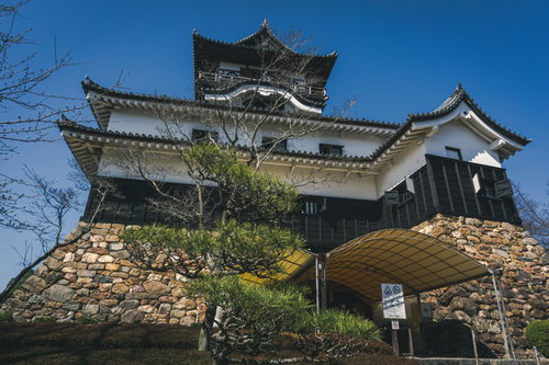 天守閣の地下二階にあたる石垣に作られた出入口にあるテントと、青空に堂々とそびえる天守閣