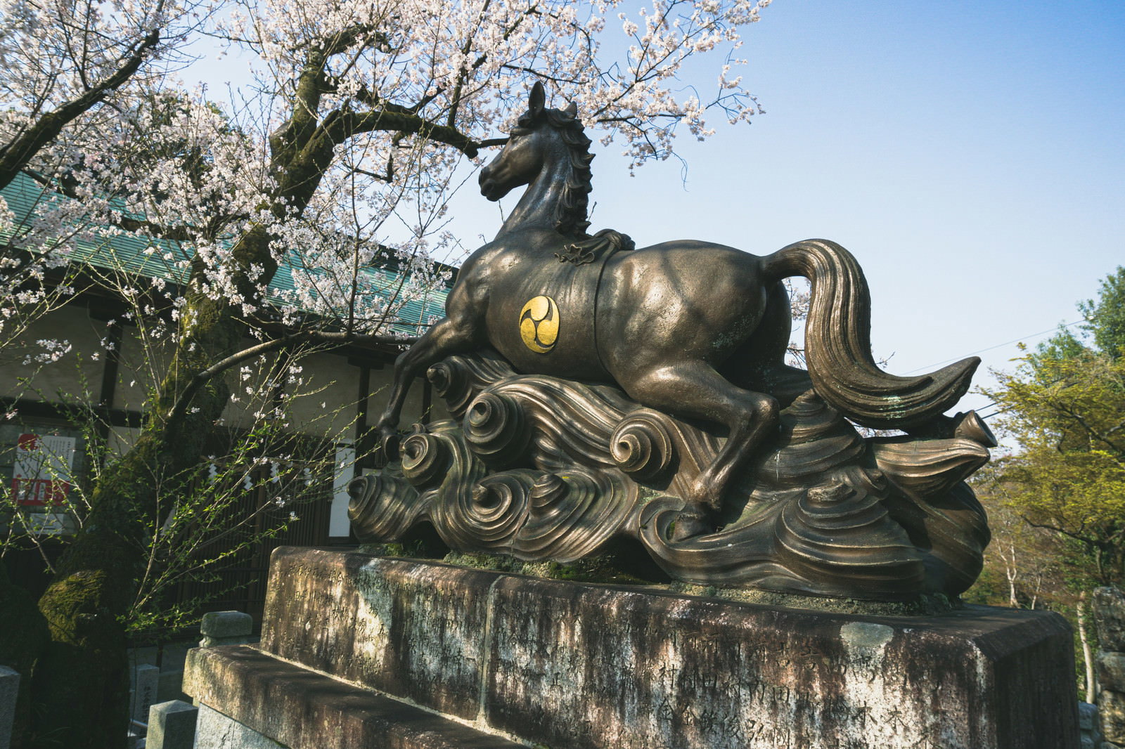 桜が咲く針綱神社境内に設置された石造りの御神馬像