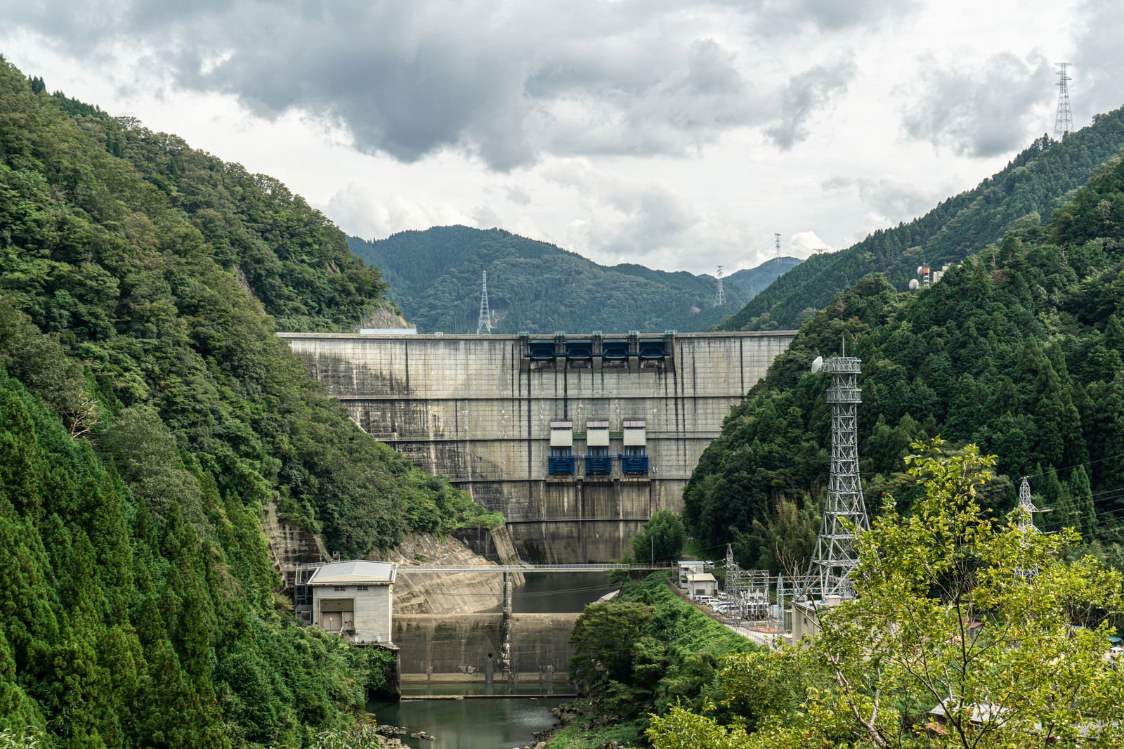 山間の緑豊かな森林に囲まれた矢作ダムの正面アーチ構造