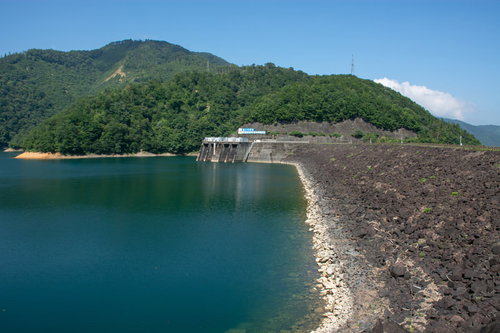 九頭竜ダム右岸より見る黒いゴツゴツした岩に覆われるダム表面と深緑の九頭竜湖