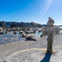 青空の下に点在する橋杭岩の奇岩群と穏やかな海面の写真