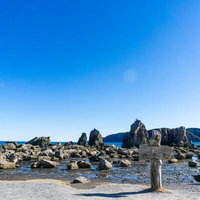 快晴の青空と強い太陽光が照らす橋杭岩の岩礁群とくしもと大橋の写真