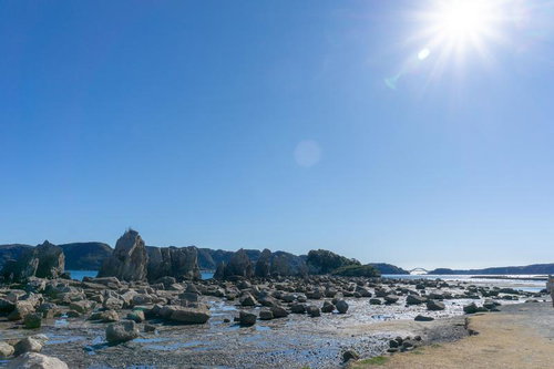 干潮時の海岸に無数に広がる橋杭岩と青空の風景