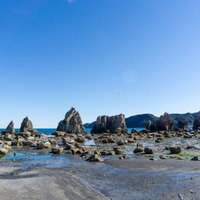 干潮時に現れる広い砂浜と一直線に並ぶ橋杭岩の写真