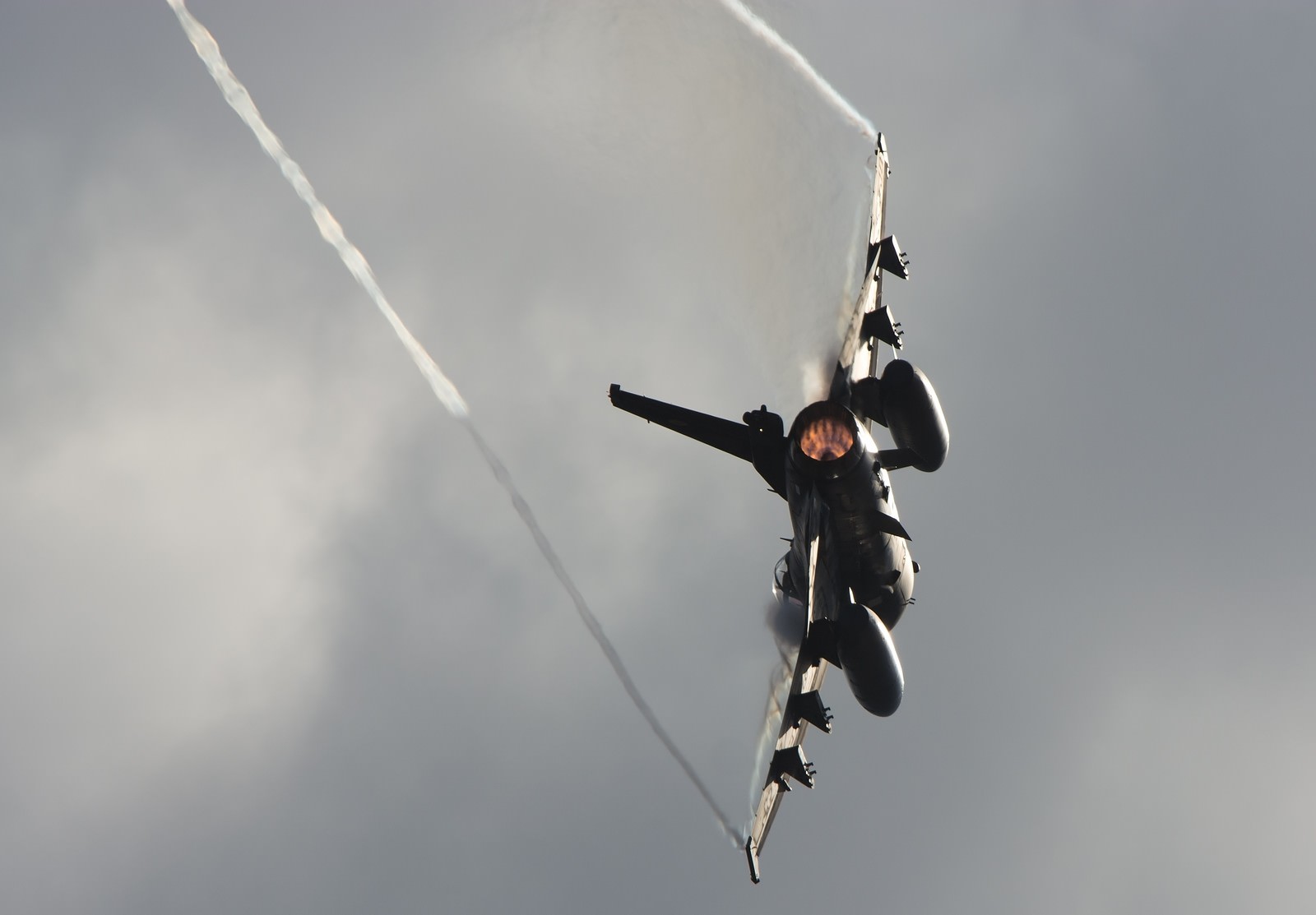 ベイパートレイルを引くF-2戦闘機の機動飛行