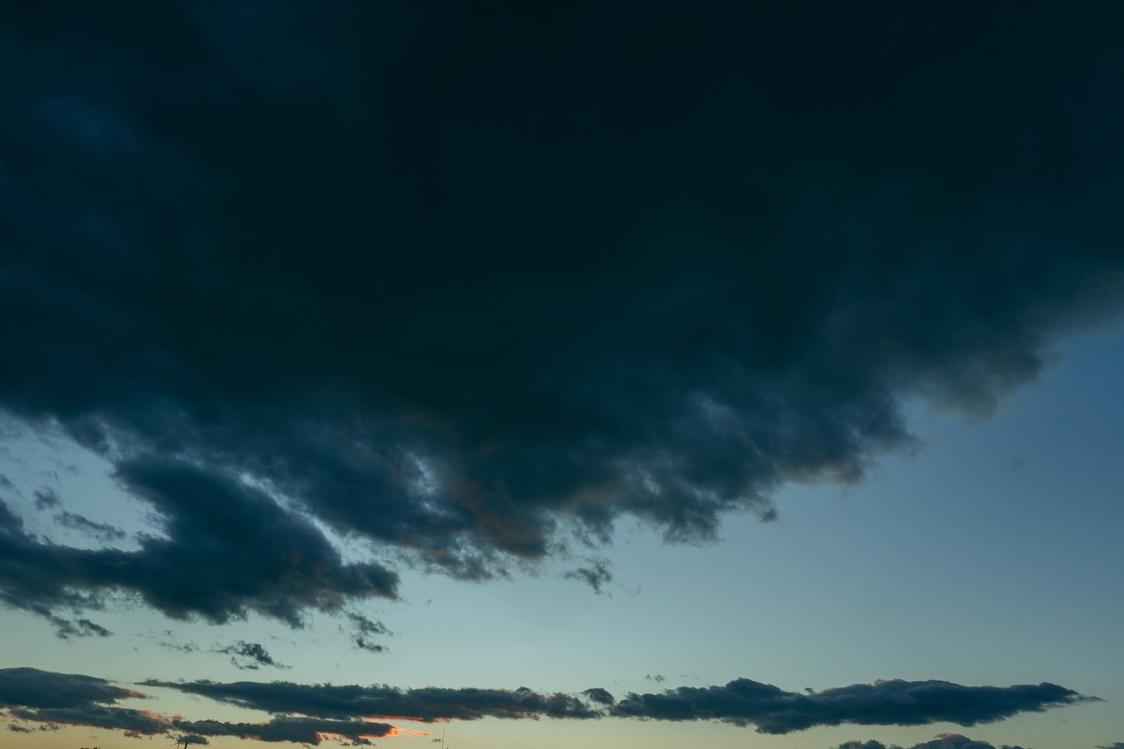赤みを帯びた夕焼けの空に黒い雲が広がる風景