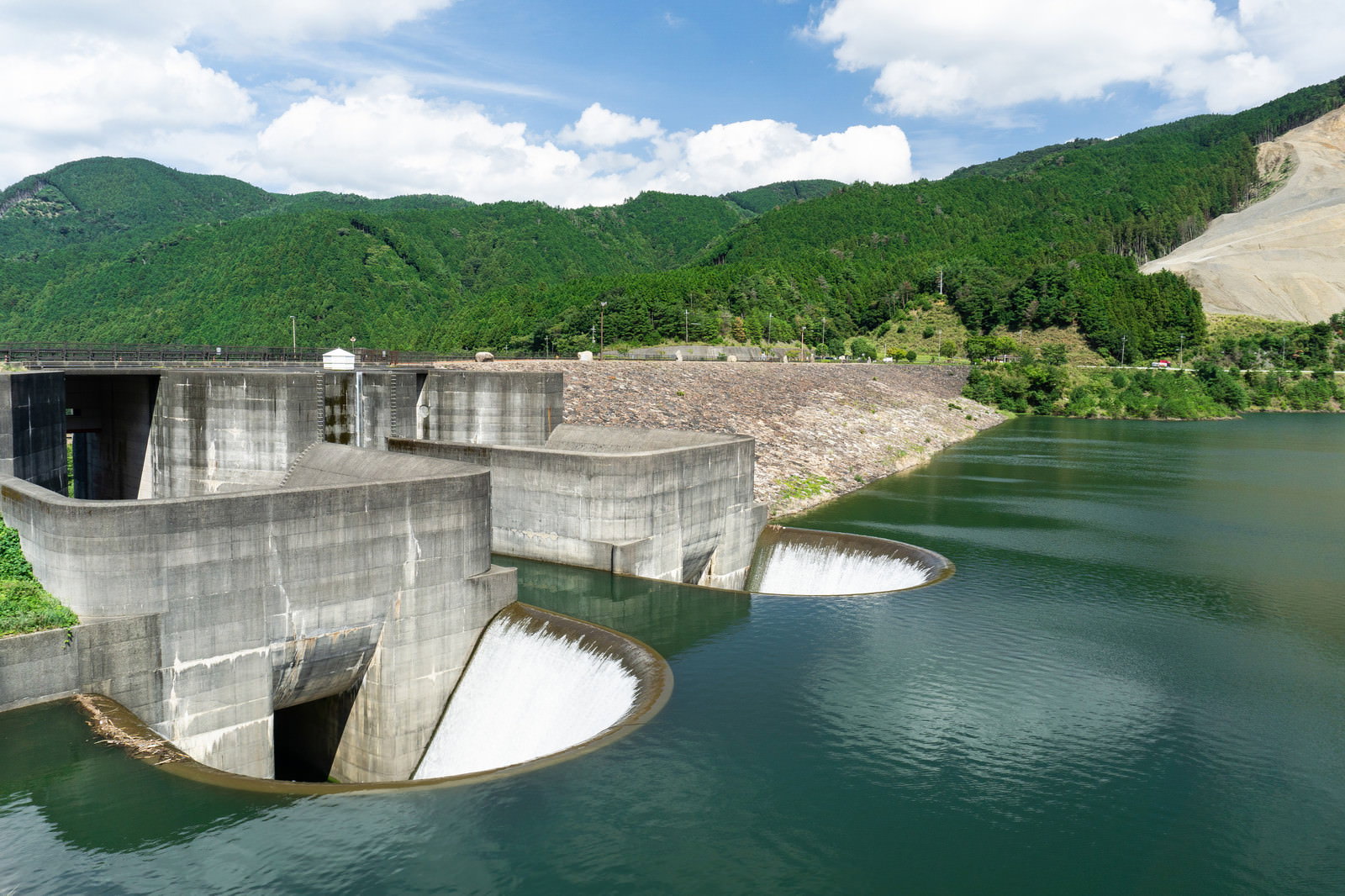 青土ダムの洪水吐施設と石組み、緑の山々に囲まれた湖