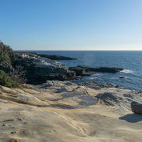 千畳敷の砂岩層と青い海が広がる岩場海岸の写真