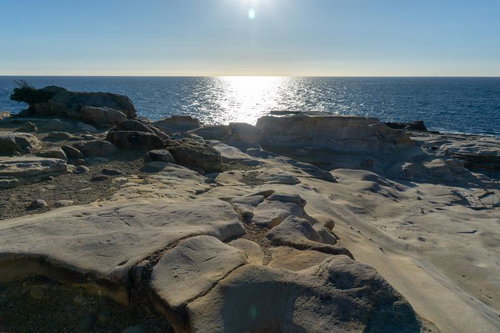 太陽光が反射する千畳敷の岩場と青い海