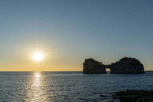 白浜の円月島に沈む夕日とオレンジに染まる海面