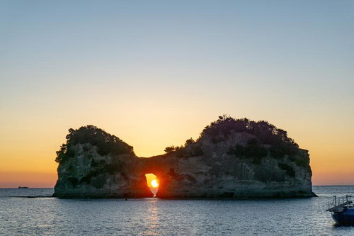円月島の穴に沈む夕陽と海に反射するオレンジの光