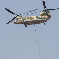 機体下部にワイヤーで消火バケットを吊るしフライトするCH47の写真