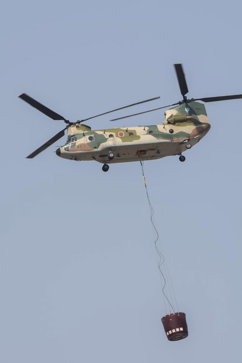 機体下部にワイヤーで消火バケットを吊るしフライトするCH47