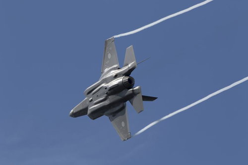 機体下面に光を受け翼端からベイパーを伸ばし青空を引き裂くF35