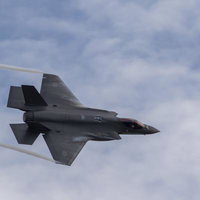 雲が広がる小松基地上空をF35戦闘機が翼の上や翼端からベイパーを発生させて機動飛行を行うの写真