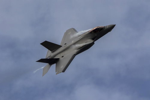 柔らかな雲が浮かぶ空を肩口からベイパーを出して機動飛行を行うF35の姿