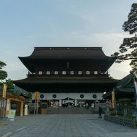 早朝の淡い光の中に堂々たる姿を見せる善光寺山門の写真