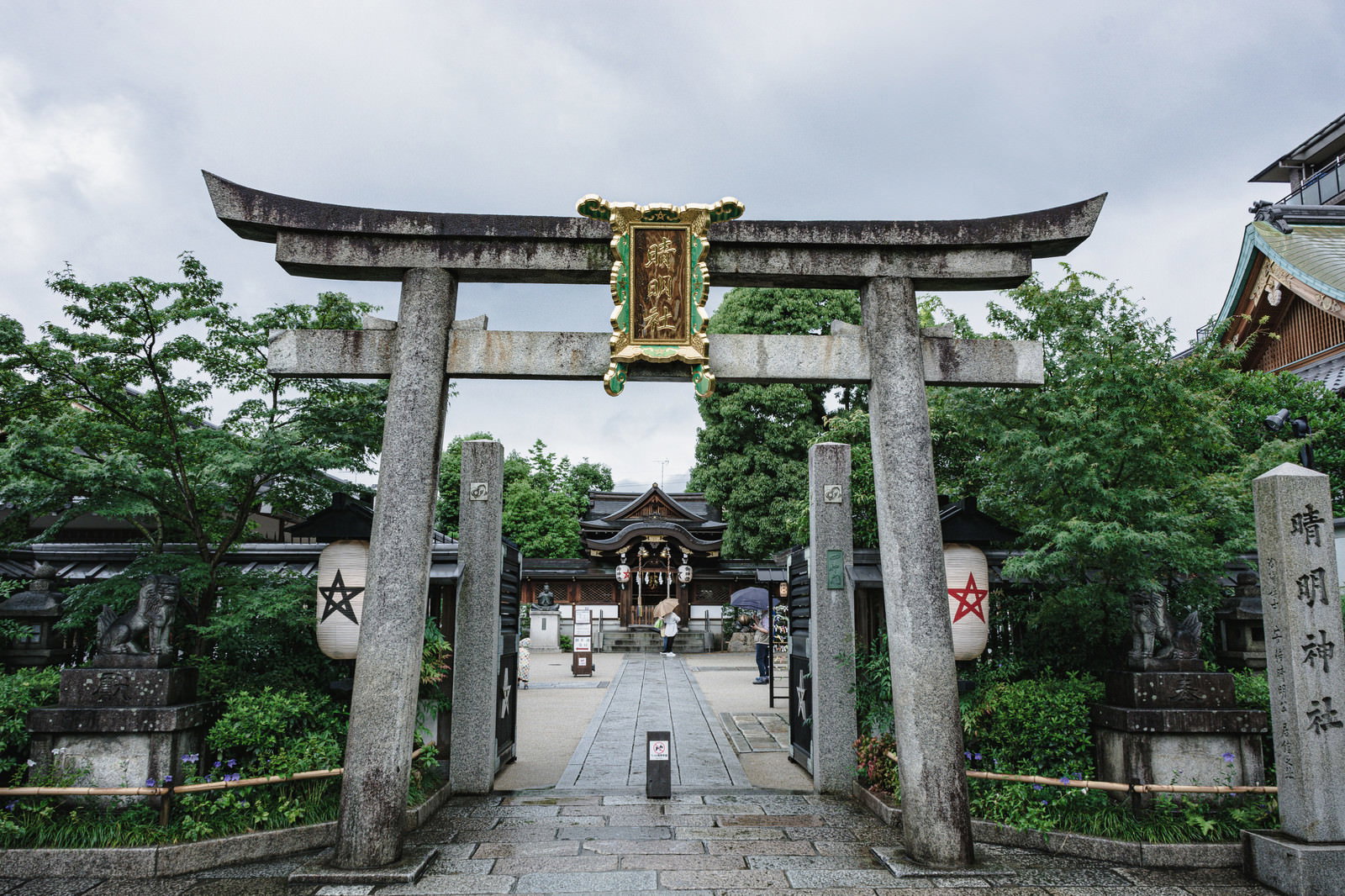 清明神社の鳥居越しに石畳の参道と緑豊かな境内が見える風景