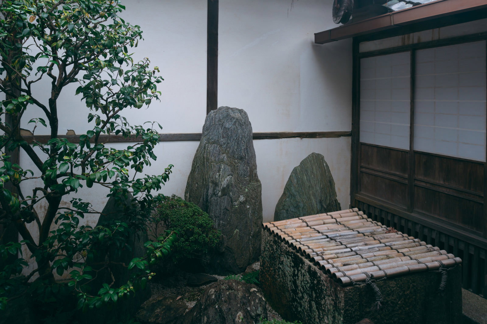 桂春院清浄の庭にある木製の井筒と石組み、背景に格子戸のある建物