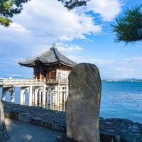 浮御堂を背景にして建つ「比良三上雪さしわたせ鷺の橋」と刻まれた松尾芭蕉の句碑の写真