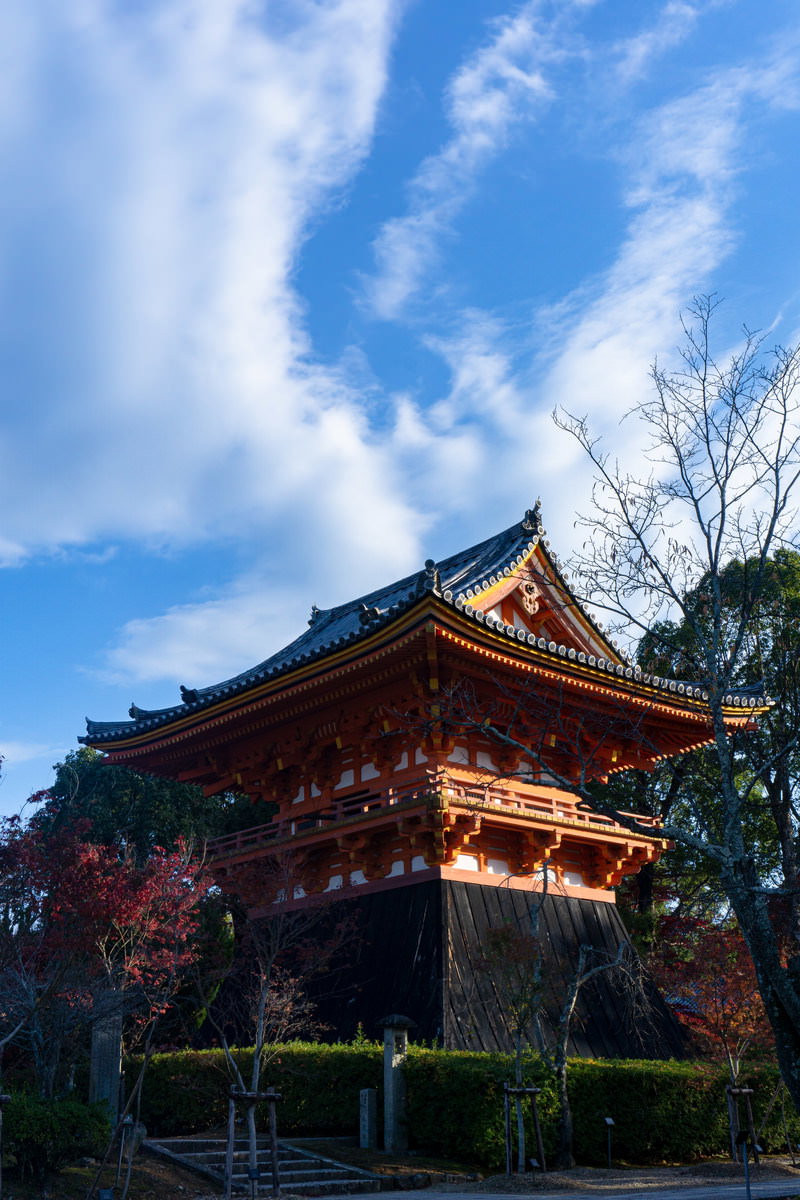 青空を背景に朱色の鐘楼が映える仁和寺の境内風景