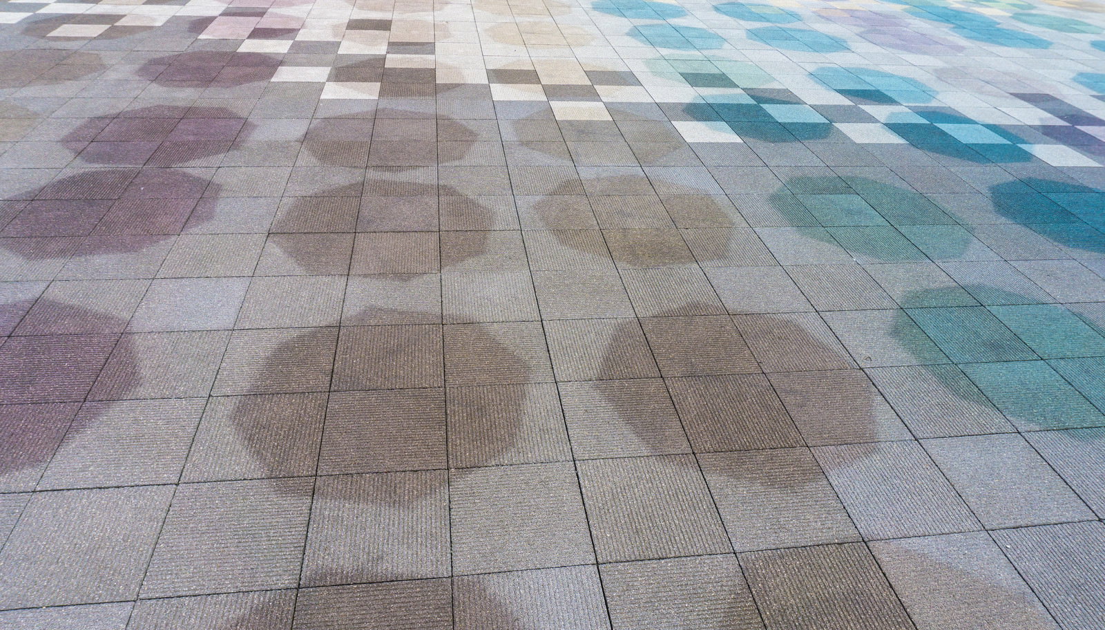 石畳の地面に映る色とりどりの傘の影