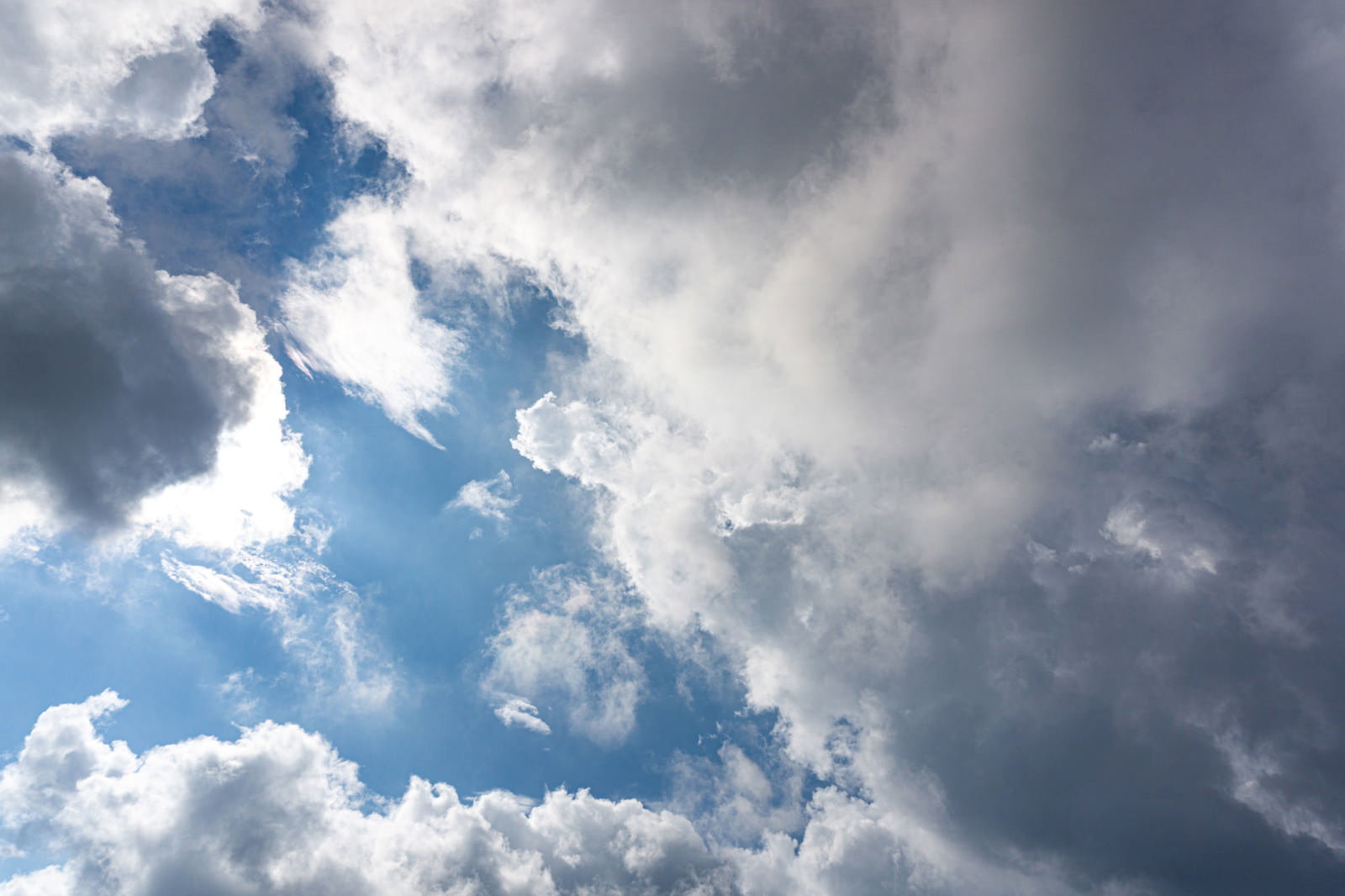 グレーと白の厚い雲が空を覆い、青空がわずかに見える曇り空