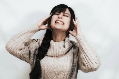 群発頭痛で顔をしかめて苦しむ女性の痛みの表情